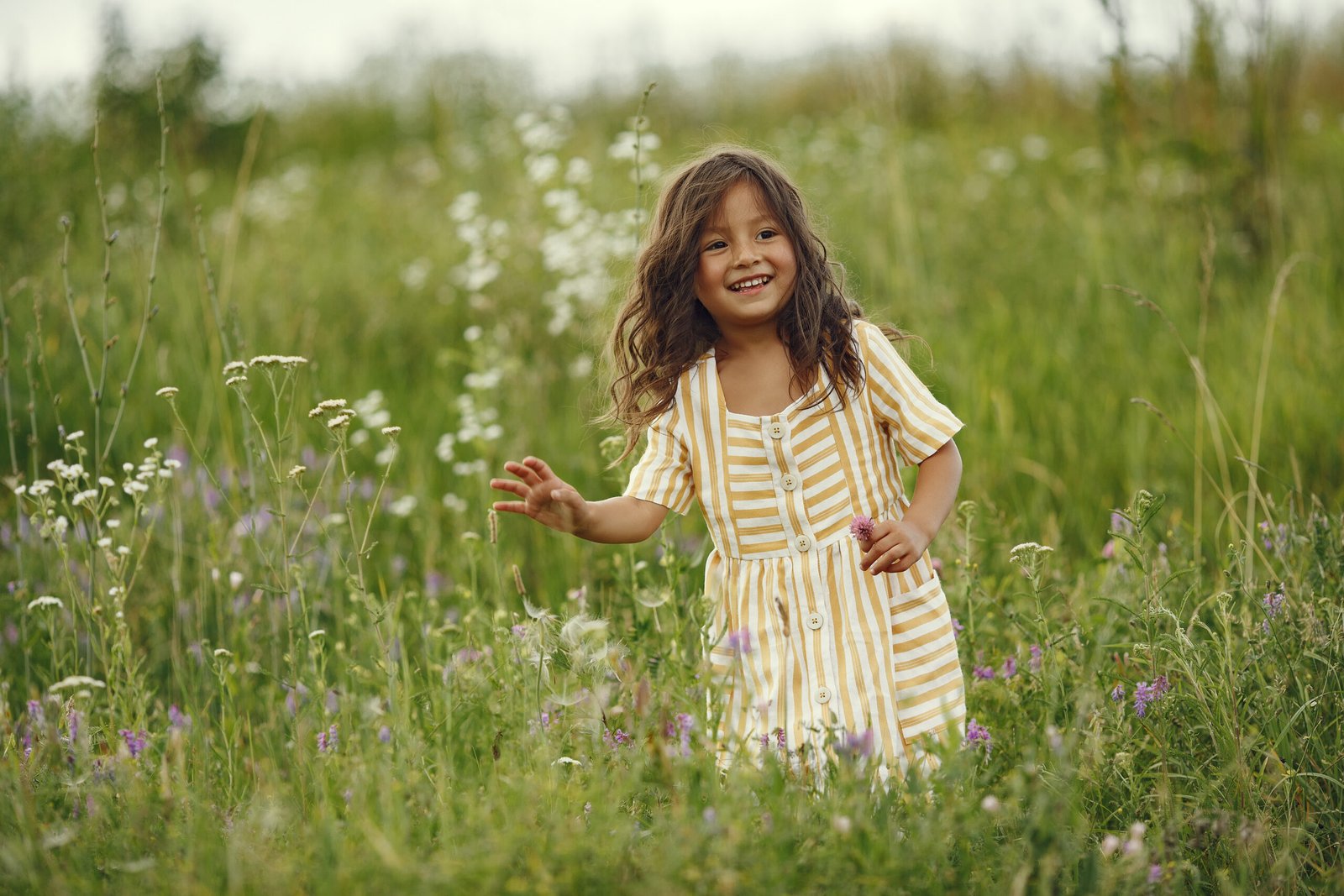 Niña en la naturaleza entre flores y alegre.
