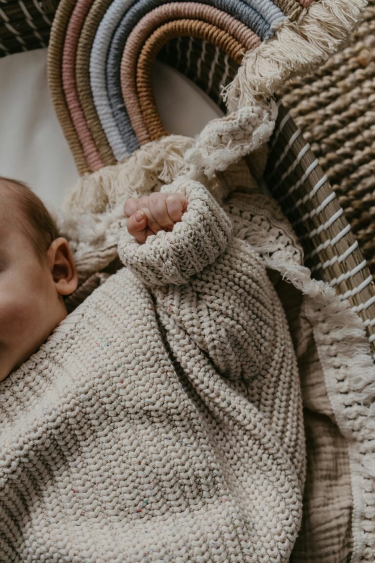 Bebé que con jersey de lana que se encuentra cómodo en una cuna con juguetes alrededor.